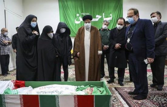 图为伊朗司法部长和法克里扎德的家人站在他的遗体旁